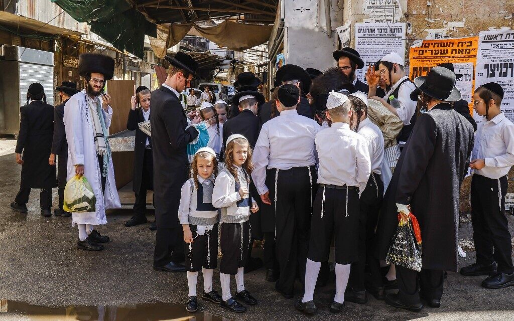 Ultra-Orthodox Jewish men and boys, a few mask-clad due to the coronavirus pandemic, stand along a street corner in the neighborhood of Mea Shearim in Jerusalem a few hours before the start of Yom Kippur, on September 27, 2020 (MENAHEM KAHANA / AFP)