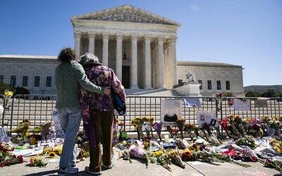 Women embrace at a makeshift memorial for late Supreme Court Justice Ruth Bader Ginsburg on the steps of the United States Supreme Court on September 20, 2020, in Washington, DC. (Alex Edelman/ Getty Images/AFP)