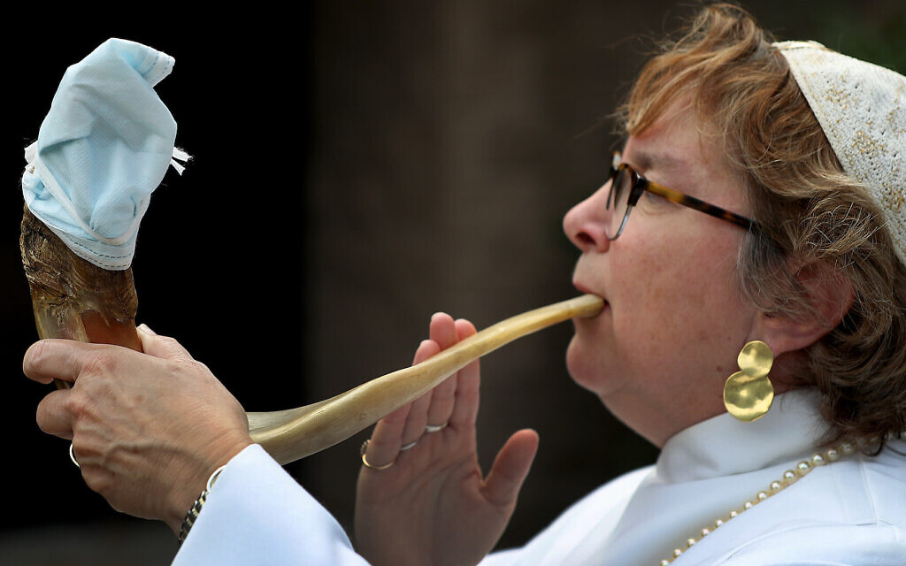 Rabbi Andrea Gouze of Easton, Massachusetts, demonstrates how she will blow the traditional shofar during the High Holidays services. The end will be covered with a face mask to prevent transmission of virus. (David L. Ryan/The Boston Globe via Getty Images via JTA) Rabbi Andrea Gouze of Easton, Massachusetts, demonstrates how she will blow the traditional shofar during the High Holidays services. The end will be covered with a face mask to prevent transmission of virus. (David L. Ryan/The Boston Globe via Getty Images via JTA)