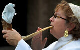 Rabbi Andrea Gouze of Easton, Massachusetts, demonstrates how she will blow the traditional shofar during the High Holidays services. The end will be covered with a face mask to prevent transmission of virus. (David L. Ryan/The Boston Globe via Getty Images via JTA)