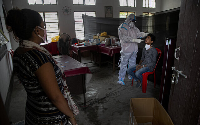 An Indian health worker takes a nasal swab sample of a man to test for COVID-19 as a woman waits for her turn in Gauhati, India, September 6, 2020. (Anupam Nath/AP) An Indian health worker takes a nasal swab sample of a man to test for COVID-19 as a woman waits for her turn in Gauhati, India, September 6, 2020. (Anupam Nath/AP)