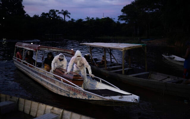 SOS Funeral workers transport by boat the coffin containing the body of a suspected COVID-19 victim that died in a river-side community near Manaus, Brazil on May 14, 2020. The victim, an 86-year-old woman, lived by the Negro river, the largest tributary to the Amazon river. (AP/Felipe Dana)