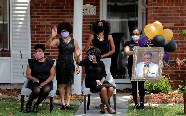 The family of Larry Hammond wave as a line of cars with friends and family, who could not attend his funeral because of limits of gatherings of more than 10 people, due to the coronavirus pandemic, pass by their home, in New Orleans, April 22, 2020. (AP/Gerald Herbert)