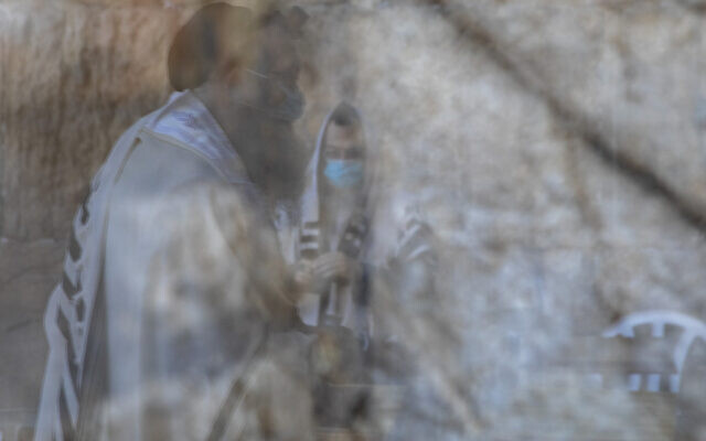 Ultra-Orthodox Jewish men wearing face masks are reflected on a door window as they pray ahead of Yom Kippur, the holiest day in the Jewish year, which starts at sundown Sunday during a three-week nationwide lockdown to curb the spread of the coronavirus at the Western Wall, the holiest site where Jews can pray, in Jerusalem's Old City, September 27, 2020. (AP Photo/Ariel Schalit) Ultra-Orthodox Jewish men wearing face masks are reflected on a door window as they pray ahead of Yom Kippur, the holiest day in the Jewish year, which starts at sundown Sunday during a three-week nationwide lockdown to curb the spread of the coronavirus at the Western Wall, the holiest site where Jews can pray, in Jerusalem's Old City, September 27, 2020. (AP Photo/Ariel Schalit)