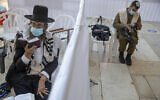With a social distancing barrier, an ultra-Orthodox Jewish man and an Israeli soldier pray ahead of Yom Kippur at the Western Wall in Jerusalem's Old City, September 27, 2020. (AP Photo/Ariel Schalit)