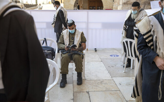 With social distancing, an Israeli soldier and ultra-Orthodox Jewish men pray ahead of Yom Kippur, the holiest day in the Jewish year, which starts at sundown Sunday during a three-week nationwide lockdown to curb the spread of the coronavirus at the Western Wall, the holiest site where Jews can pray in Jerusalem's Old City, September 27, 2020. (AP Photo/Ariel Schalit) With social distancing, an Israeli soldier and ultra-Orthodox Jewish men pray ahead of Yom Kippur, the holiest day in the Jewish year, which starts at sundown Sunday during a three-week nationwide lockdown to curb the spread of the coronavirus at the Western Wall, the holiest site where Jews can pray in Jerusalem's Old City, September 27, 2020. (AP Photo/Ariel Schalit)