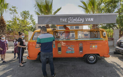 Emad Abdeljawwad sells grilled hot dogs and beverages out of a converted van in the West Bank city of Ramallah, Sept. 23, 2020. With dine-in restaurants mostly closed due to health restrictions, food trucks have allowed entrepreneurial palestinian businessmen to find a way to keep working. (AP/Nasser Nasser)