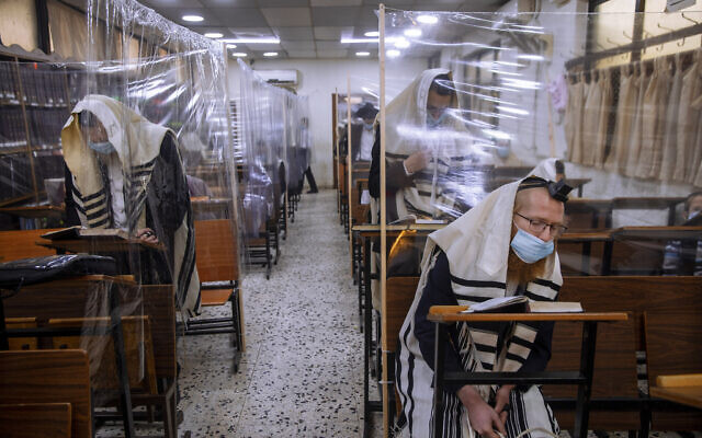 In this Monday, September 21, 2020 file photo, ultra-Orthodox Jews wear face masks during a morning prayer in a synagogue separated by plastic partitions, in Bnei Brak, Israel. (AP/Oded Balilty, File) In this Monday, September 21, 2020 file photo, ultra-Orthodox Jews wear face masks during a morning prayer in a synagogue separated by plastic partitions, in Bnei Brak, Israel. (AP/Oded Balilty, File)