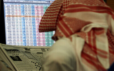 A Saudi man reads a newspaper while keeping an eye on a screen displaying stock market figures, at al Jazeera Capital Bank in Riyadh, Saudi Arabia, March 19, 2008. (Hasan Jamali/AP)