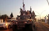 ISIS fighters parade in commandeered Iraqi security forces armored vehicles down a main road at the northern city of Mosul, Iraq, more than two weeks after taking over the country's second largest city, June 23, 2014. (AP Photo)
