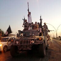 ISIS fighters parade in commandeered Iraqi security forces armored vehicles down a main road at the northern city of Mosul, Iraq, more than two weeks after taking over the country's second largest city, June 23, 2014. (AP Photo)
