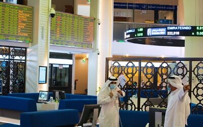 Two Emiratis wearing face masks due to the coronavirus pandemic talk on the floor of the Dubai Financial Market in Dubai, United Arab Emirates, July 7, 2020 (AP Photo/Jon Gambrell)