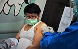 A medical worker gives coronavirus vaccine candidate to a volunteer during a trial at a community health center in Bandung, West Java, Indonesia, Friday, Aug. 14, 2020. Indonesia's only vaccine production company has started this week a so-called phase 3 clinical trials to test a potential coronavirus vaccine developed by a Chinese company. (AP Photo/Kusumadirezza)