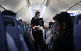 A flight attendant hands out chocolates with a greeting card to passengers on an El Al plane from Israel en route to Abu Dhabi, United Arab Emirates, Monday, Aug. 31, 2020. (Nir Elias/Pool Photo via AP)
