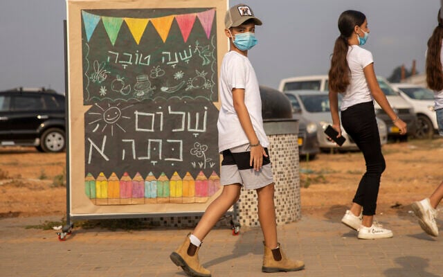 Elementary school students wearing masks amid the coronavirus pandemic walk past a signs reads 'Happy New Year, Hello First Grade' on the first day of school in Kfar Yona, Sept. 1, 2020. (AP Photo/Ariel Schalit) Elementary school students wearing masks amid the coronavirus pandemic walk past a signs reads 'Happy New Year, Hello First Grade' on the first day of school in Kfar Yona, Sept. 1, 2020. (AP Photo/Ariel Schalit)