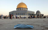 A protective face mask is left on the ground during the Eid al-Adha prayers, next to the Dome of the Rock at the Temple Mount compound in Jerusalem's Old City, July 31, 2020. (AP Photo/Mahmoud Illean, File)