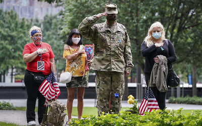 US Army Sgt. Edwin Morales, center right, salutes after placing flowers for fallen FDNY firefighter Ruben D. Correa at the National September 11 Memorial and Museum, September 11, 2020, in New York. (AP Photo/John Minchillo)