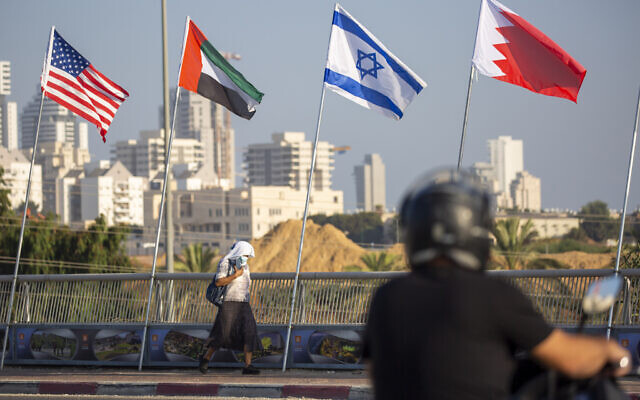 A woman wearing a face mask against the coronavirus pandemic walks past American, United Arab Emirates, Israel and Bahraini flags at the Peace Bridge in Netanya, Israel, September 14, 2020.  (AP/Ariel Schalit)