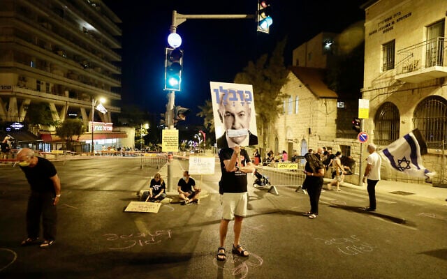 Israeli protesters hold signs and chant slogans during a demonstration against  Prime Minister Benjamin Netanyahu near the Prime Minister's residence in Jerusalem, September 20, 2020. (AP Photo/Sebastian Scheiner)