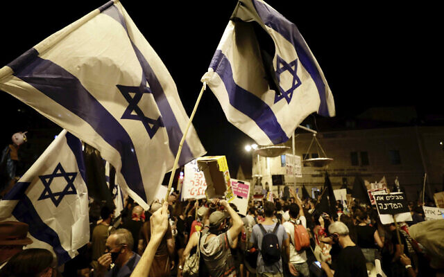 Anti-Netanyahu protesters wave flags, hold signs and chant slogans during a demonstration outside the Prime Minister's Residence in Jerusalem, September 20, 2020. (AP Photo/Sebastian Scheiner)