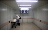 A worker from 'Hevra Kadisha,' Israel's official Jewish burial society, prepares a body before a funeral procession at a special morgue for COVID-19 victims in Holon, September 23, 2020 (AP Photo/Oded Balilty)