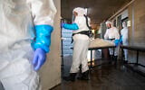 Workers from 'Hevra Kadisha,' Israel's official Jewish burial society, prepare a body before a funeral at a special morgue for COVID-19 victims in Holon, Sept. 23, 2020 (AP Photo/Oded Balilty)