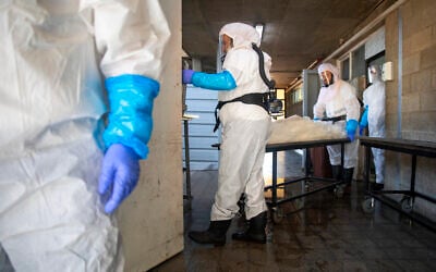 Workers from 'Hevra Kadisha,' Israel's official Jewish burial society, prepare a body before a funeral at a special morgue for COVID-19 victims in Holon, Sept. 23, 2020 (AP Photo/Oded Balilty) Workers from 'Hevra Kadisha,' Israel's official Jewish burial society, prepare a body before a funeral at a special morgue for COVID-19 victims in Holon, Sept. 23, 2020 (AP Photo/Oded Balilty)