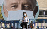 A woman walks past a banner encouraging people to wear face masks in Tel Aviv, Israel, Sept. 24, 2020. (AP/Sebastian Scheiner)