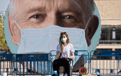A woman walks past a banner encouraging people to wear face masks in Tel Aviv, Israel, Sept. 24, 2020. (AP/Sebastian Scheiner)