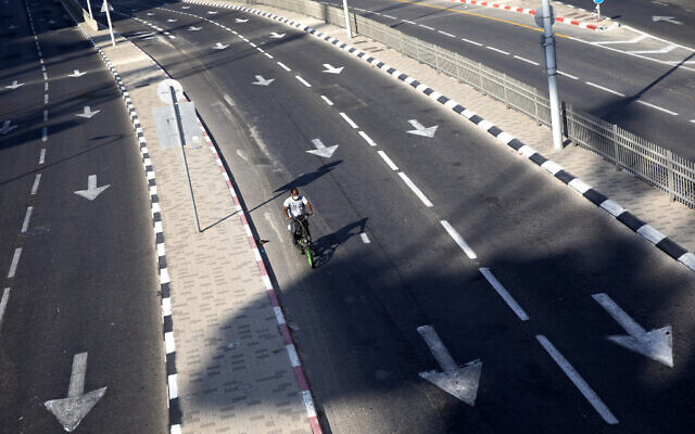 A man rides his bicycle on a slow traffic road following restrictions in the  nationwide lockdown, in Tel Aviv, Israel, Sept 25, 2020. (AP Photo/Oded Balilty)