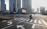 A man rides a bicycle next to a billboard calling people to wear masks, on empty road following new restrictions in the three-week nationwide lockdown, in Tel Aviv, Israel, Sept. 26, 2020. (AP Photo/Oded Balilty)