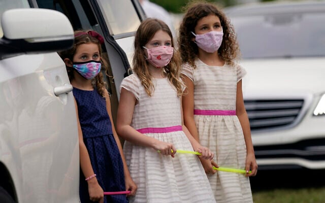 Ariela Klepacz, left, Sarah Halpern, center, and Gabriela Klepacz, right, stand outside of their vehicle during a Yom Kippur service hosted by the Aventura Turnberry Jewish Center, during the coronavirus pandemic, Sept. 28, 2020, at the Dezerland Park drive-in theatre in North Miami, Florida (AP Photo/Lynne Sladky)