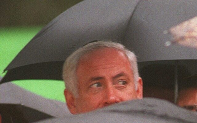 The face of Prime Minister Benjamin Netanyahu is seen through a multitude of umbrellas during a memorial for Israel's former Premier Levi Eshkol held on February 23, 1997, in Jerusalem's Har Herzl cemetery. (AP/Nati Harnik) The face of Prime Minister Benjamin Netanyahu is seen through a multitude of umbrellas during a memorial for Israel's former Premier Levi Eshkol held on February 23, 1997, in Jerusalem's Har Herzl cemetery. (AP/Nati Harnik)