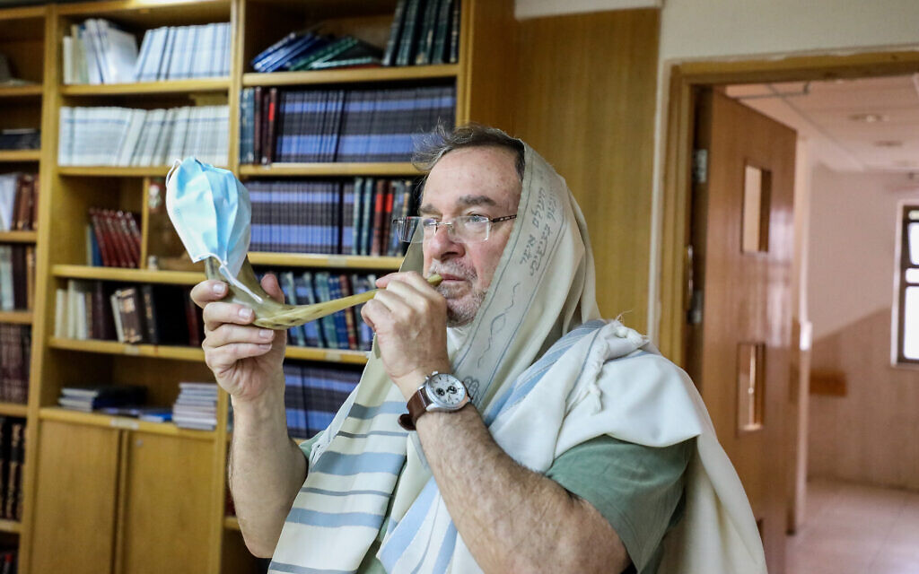 Illustrative: A man blows a shofar covered with a face mask at a synagogue in the West Bank settlement of Efrat on August 21, 2020. (Gershon Elinson/Flash90) Illustrative: A man blows a shofar covered with a face mask at a synagogue in the West Bank settlement of Efrat on August 21, 2020. (Gershon Elinson/Flash90)
