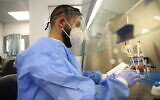 A technician carries out a diagnostic test for coronavirus in a lab at the Ziv Medical Center, in the northern city of Safed on August 24, 2020. (David Cohen/Flash90)