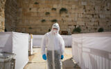 An Orthodox Jewish talmudic seminary student wearing protectives suit, gloves, face mask and a face shield prays at the Western Wall in the Old City of Jerusalem, September 3, 2020. (Olivier Fitoussil/Flash90)