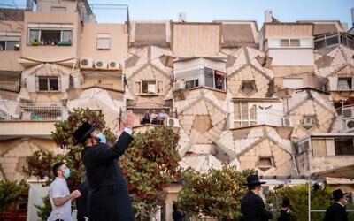 Ultra orthodox Jewish men pray outside an apartment building in the neighborhood of Ramot, in Jerusalem on September 9, 2020. (Yonatan Sindel/Flash90)