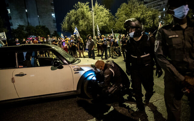 Police officers search the car of a man who sped toward police and demonstrators during a protest against Prime Minister Benjamin Netanyahu, outside his official residence in Jerusalem on September 20, 2020. (Yonatan Sindel/Flash90)