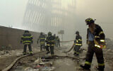 Firefighters work beneath the destroyed mullions, the vertical struts that once faced the outer walls of the World Trade Center towers, after the terrorist attack on the twin towers in New York, September 11, 2001. (AP Photo/Mark Lennihan, File)