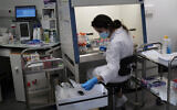A lab technician prepares chemicals to process COVID-19 tests in Argenteuil, near Paris, Sept. 25, 2020. (AP Photo/Francois Mori)
