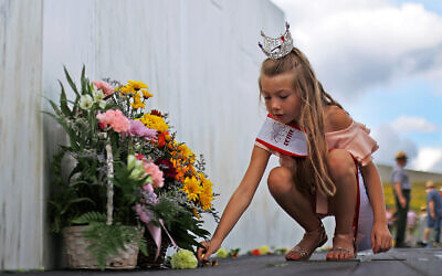 A girl places a flower at the Wall of Names at the Flight 93 National Memorial in Shanksville, Pennsylvania, Sept. 10, 2020. (AP Photo/Gene J. Puskar)