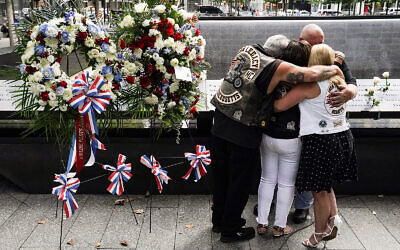 Mourners hug beside the names of the deceased at the National September 11 Memorial and Museum in New York, September 11, 2020. (AP Photo/John Minchillo)