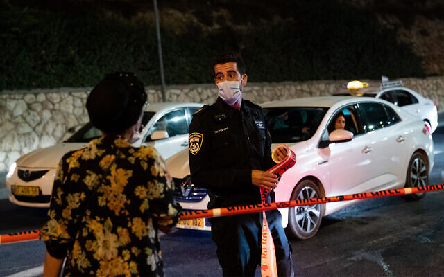 Police at the entrance to the neighborhood of Ramot in Jerusalem as a coronavirus curfew goes into effect, September 8, 2020. (Yonatan Sindel/Flash90) Police at the entrance to the neighborhood of Ramot in Jerusalem as a coronavirus curfew goes into effect, September 8, 2020. (Yonatan Sindel/Flash90)