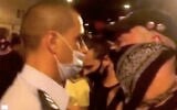 Jerusalem police officer Koby Yaakobi wears a mask with his nose exposed while standing among a crowd of protesters demonstrating against Prime Minister Benjamin Netanyahu outside his official residence in Jerusalem on Sunday, September 20, 2020. (Screen capture/Ynet News)