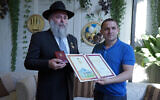 Rabbi Yonatan Markovitch, left, holds up a medal and a certificate he received at the parliament of Ukraine in Kyiv, September 7, 2020. (Courtesy of Markovitch via JTA)