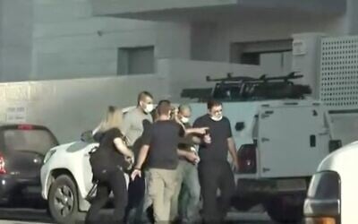 Walid Mansour, center, handcuffed, reenacts his alleged stabbing of an Israeli man at a building site in Rosh Ha'ayin. (Channel 12 news)