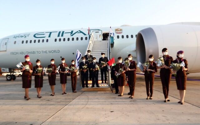 The crew of an Etihad Airlines flight wave Israeli flags after landing at Ben Gurion Airport, October 19, 2020 (Sivan Farag) The crew of an Etihad Airlines flight wave Israeli flags after landing at Ben Gurion Airport, October 19, 2020 (Sivan Farag)