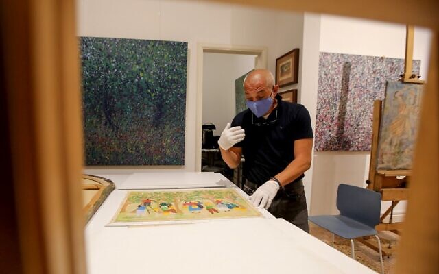 Gaby Maamary, a Lebanese artwork conservation specialist, examines a painting by late Lebanese artist Sophie Yeramian, damaged in the Beirut port blast, at his studio in the capital Beirut on September 17, 2020 (ANWAR AMRO / AFP) Gaby Maamary, a Lebanese artwork conservation specialist, examines a painting by late Lebanese artist Sophie Yeramian, damaged in the Beirut port blast, at his studio in the capital Beirut on September 17, 2020 (ANWAR AMRO / AFP)