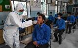 A health official (L) collects a swab sample from a student to test for the Covid-19 coronavirus at a government school in Lahore on October 1, 2020, after the educational institutes reopened nearly six months after the spread of the Covid-19 coronavirus. (Arif ALI / AFP)