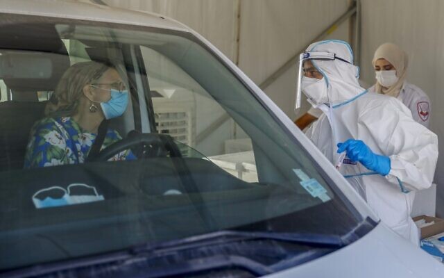 A paramedic with Israel's Magen David Adom medical services speaks with a driver at a drive-thru COVID-19 testing center in Jerusalem on October 7, 2020 (AHMAD GHARABLI / AFP) A paramedic with Israel's Magen David Adom medical services speaks with a driver at a drive-thru COVID-19 testing center in Jerusalem on October 7, 2020 (AHMAD GHARABLI / AFP)